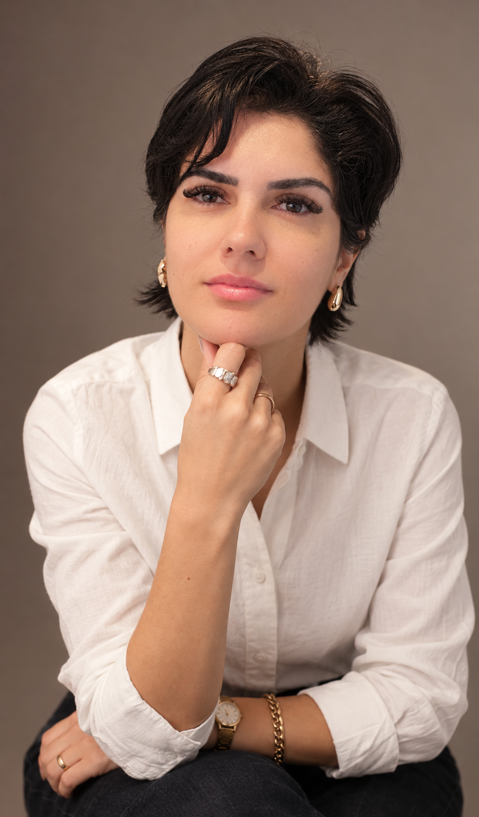 Retrato de Joice Paula Cavalcante, de camisa branca, com a mão sob o queixo.